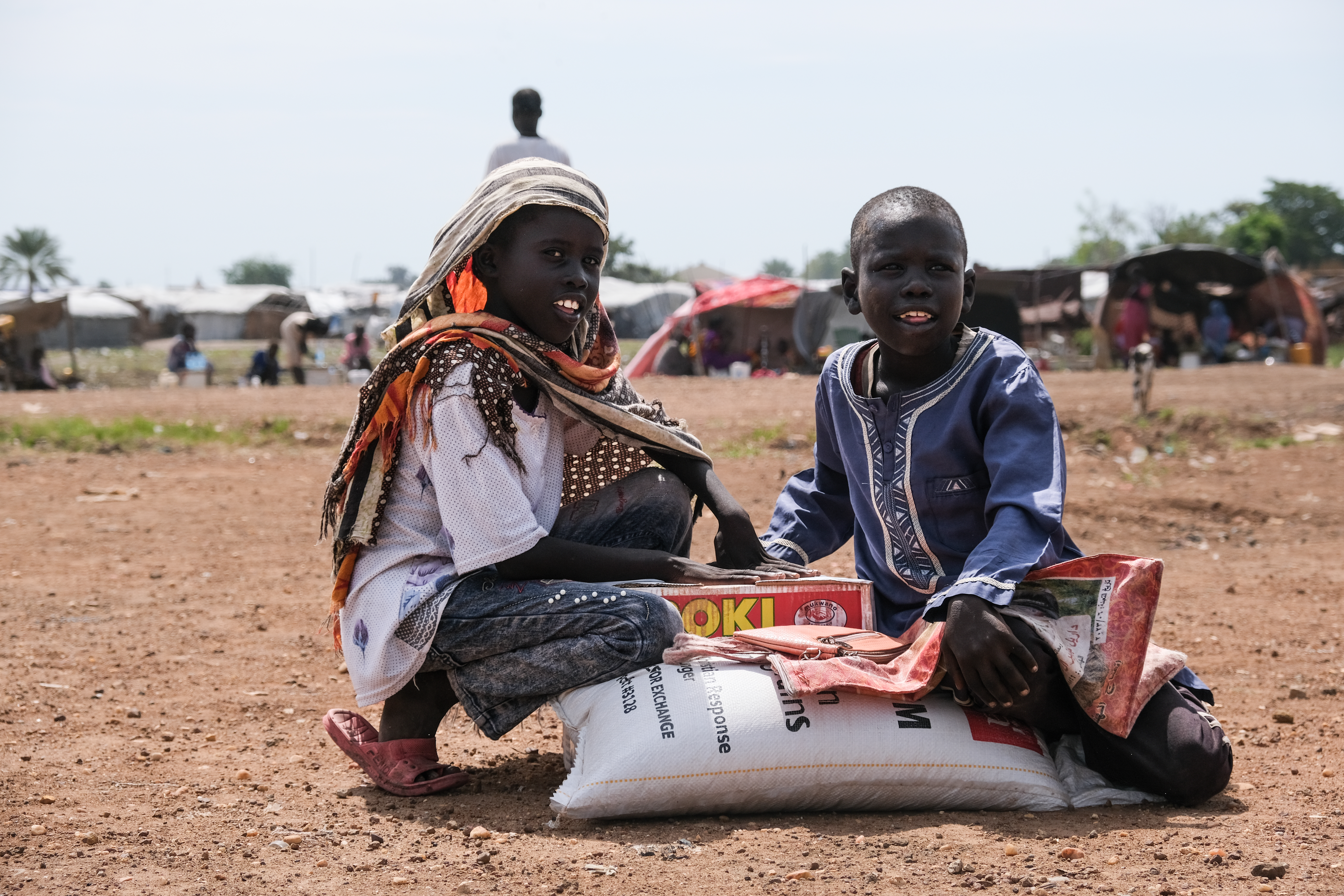 Zero Mawang Juch (left) and Sudan Koang Ruei at the distribution site with a portion of food supplies. Each bag of sorghum is about 15kgs, so it is heavy for program participants to carry on their heads and back to their homes.