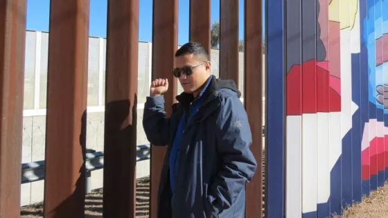 A man standing in front of a border wall