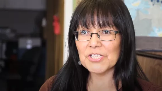 An Indigenous woman with black hair, bangs and glasses