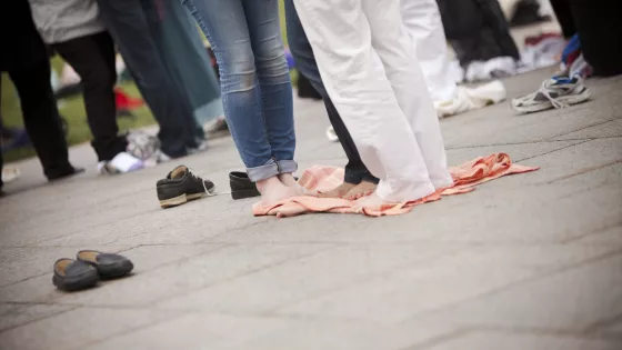 Several people stand close together on a blanket. They aren't wearing shoes.
