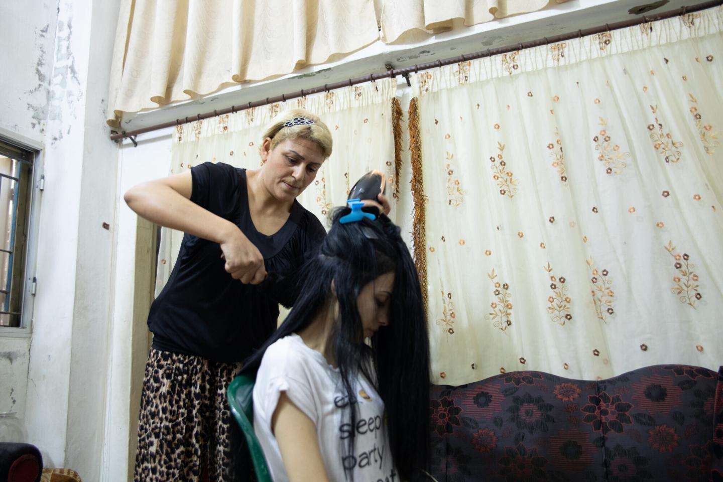 A woman brushes another woman's hair