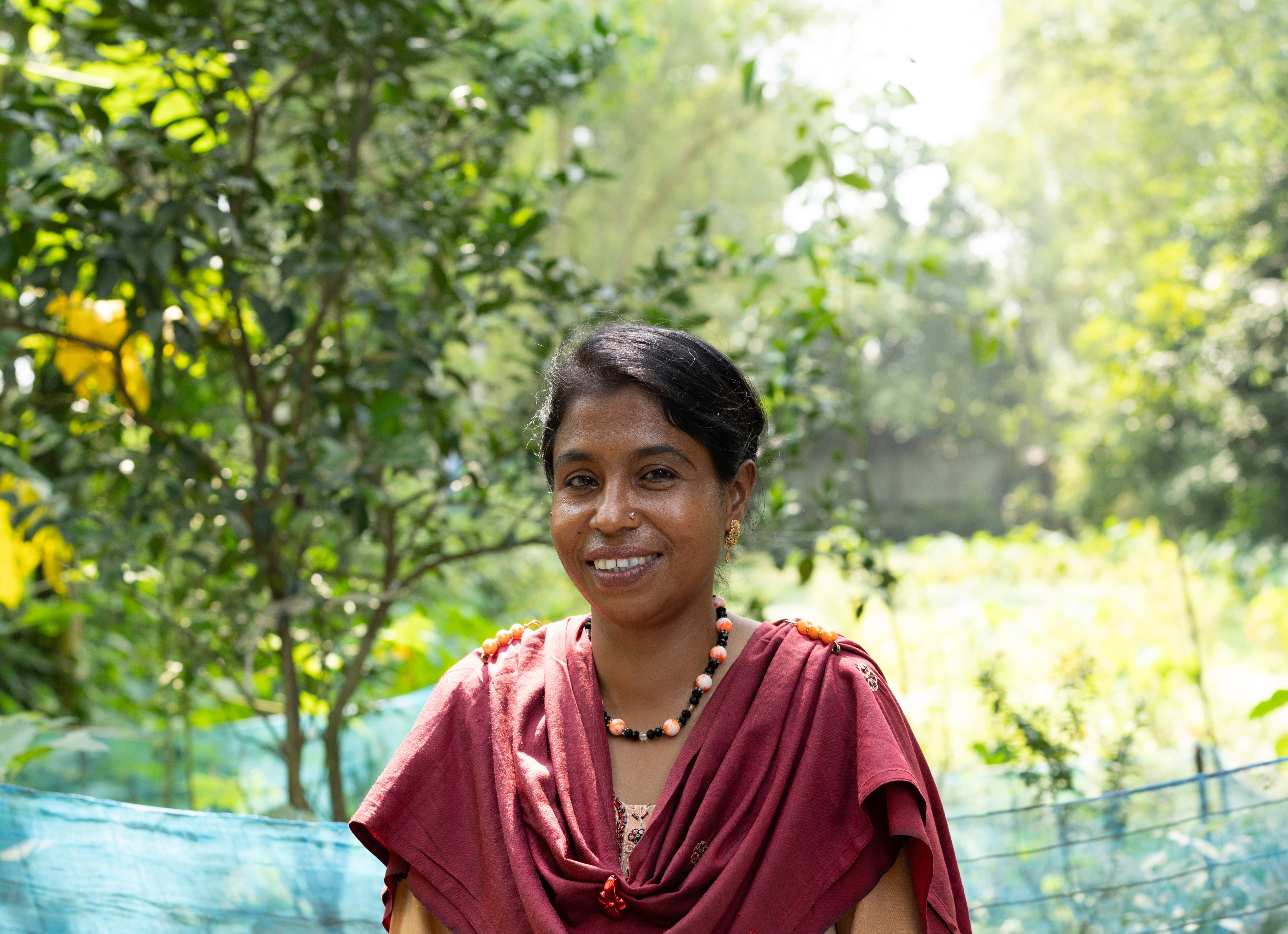 A woman smiling in front of a lush forest