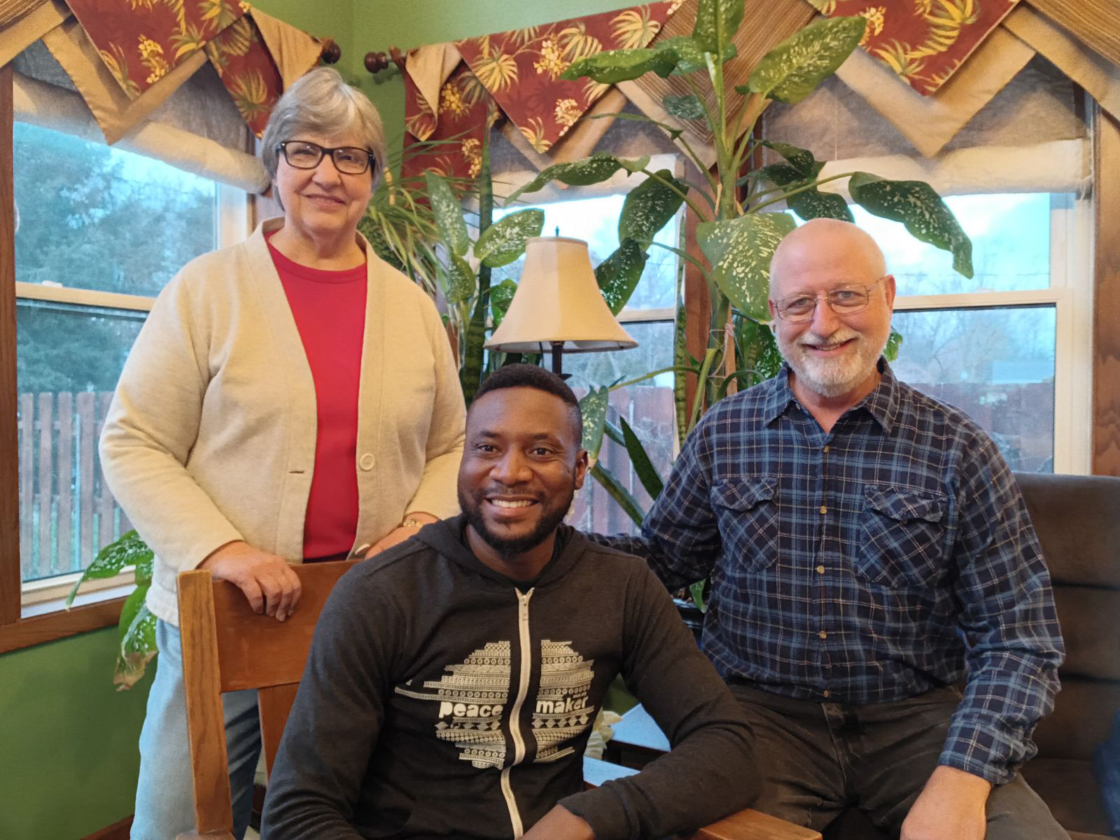 A young man smiles for a photo with an older couple