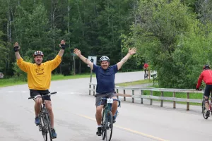 Two male cyclist in an open road with hands raised