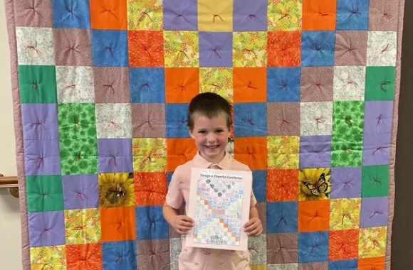 Isaac Eby stands in front of the "Cheerful Comforter" he designed.